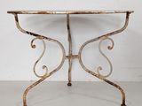 an old iron table with a glass top sitting on a white floor