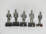 three silver figurines of men with hats and canes on wooden bases