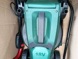 a green and black electric lawn mower in a cardboard box