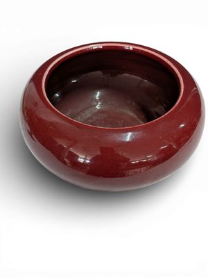un bol rouge posé sur une surface blanche
