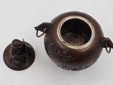 a small brown vase with a bird on it and a small figurine next to it