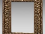 un miroir orné d'un cadre doré au motif décoratif