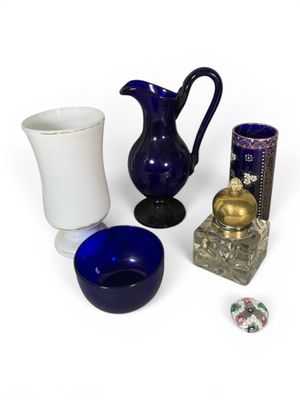 un vase bleu, un vase bleu, un vase blanc et un bol bleu posés sur une surface blanche