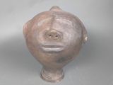 un vase marron orné d'un visage, posé sur une table