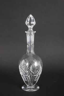 une carafe en verre transparent posée sur une surface noire, avec un fond noir