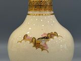 a white vase with a gold decoration on it