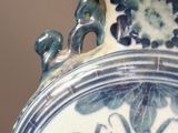 a large blue and white vase with a wooden handle