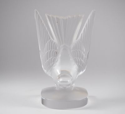 un vase en verre transparent posé sur un socle, sur une surface blanche