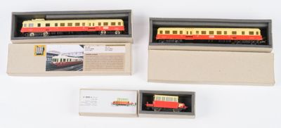 trois trains miniatures dans une boîte, posés sur une surface blanche