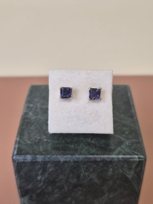 a pair of blue sapphire earrings sitting on top of a marble block