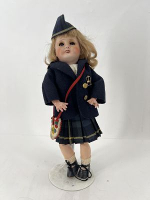 poupée en porcelaine vêtue d'un uniforme et tenant un sac à main