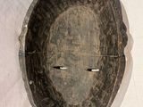 a wooden mask hanging on the wall on the wall