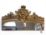 a mirror that has a gold frame with a bird on it