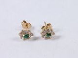 pair of emerald and diamond earrings on a white surface