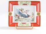 une assiette rouge et blanche sur laquelle est représenté un oiseau bleu