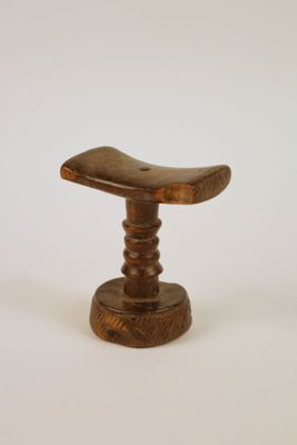 un petit tabouret en bois posé sur une surface blanche