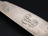 a silver spoon with a monogram on it on a black surface