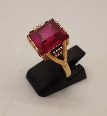 un gros plan d'une bague en pierre rouge posée sur un socle noir