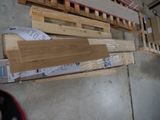 Plusieurs morceaux de bois sont empilés sur des palettes dans un garage