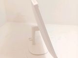a white computer monitor sitting on a stand in a room