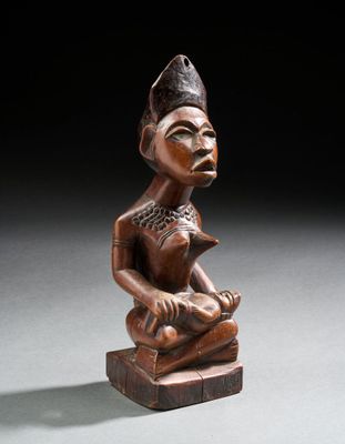 une statue en bois représentant une femme assise sur un bloc de bois