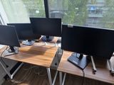 three computer monitors sitting on a desk in front of a window