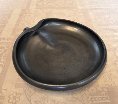 une assiette noire posée sur une table, avec une cuillère dessus
