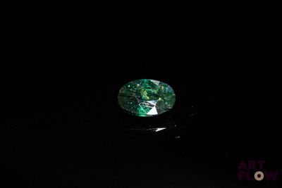 un gros plan d'un diamant vert et noir sur une surface noire