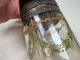 a hand holding a glass jar with a design on it