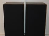 deux enceintes noires placées l'une à côté de l'autre sur un parquet