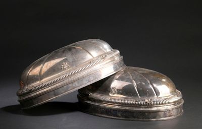 une paire d'objets plaqués argent posés sur une surface noire avec un fond noir
