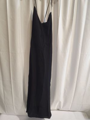 une robe noire suspendue à un cintre devant un rideau blanc