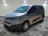 La camionnette argentée est garée sur un sol en carrelage à damier.