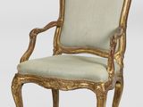 a gold and green upholstered chair with a beige upholstered seat