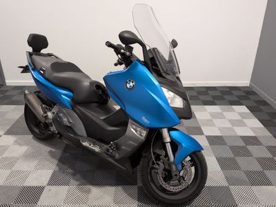 une moto bleue garée sur un sol en carrelage à damier