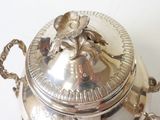 a silver container with a flower on it on a table
