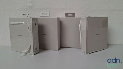 Trois boîtes blanches sont posées sur une table devant un fond blanc.