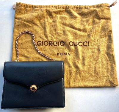 a black purse with a chain hanging from it next to a pouch