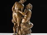 statue of a man and a woman on a rock with a black background