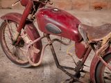 an old red motorcycle that is parked in front of a brick wall