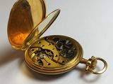 a gold pocket watch sitting on a white surface