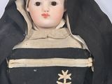 an old doll of a nun with a cross on it ' s head
