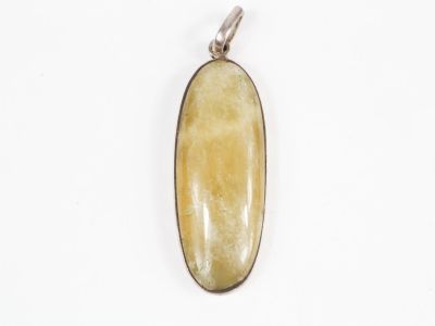 un gros plan d'un pendentif en pierre jaune posé sur une surface blanche