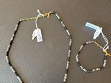 deux colliers et des bracelets posés sur une table, accompagnés d'étiquettes