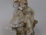 figurine représentant un garçon et une fille assis sur une souche d'arbre