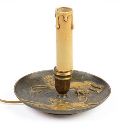 bougeoir avec une bougie posée sur une assiette, le tout sur une surface blanche