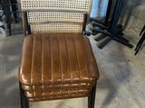 fauteuil en cuir marron avec dossier et assise tressés, dans un entrepôt