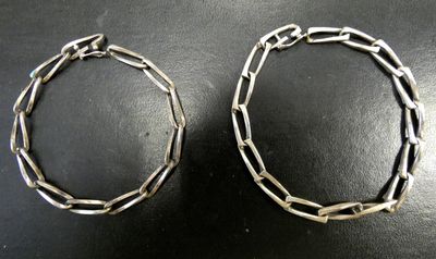 deux bracelets en argent posés sur une table avec un fond noir
