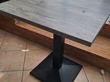 a square table with a black metal base on a tiled floor