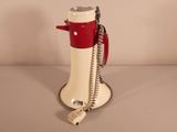 a red and white telephone that is on a stand